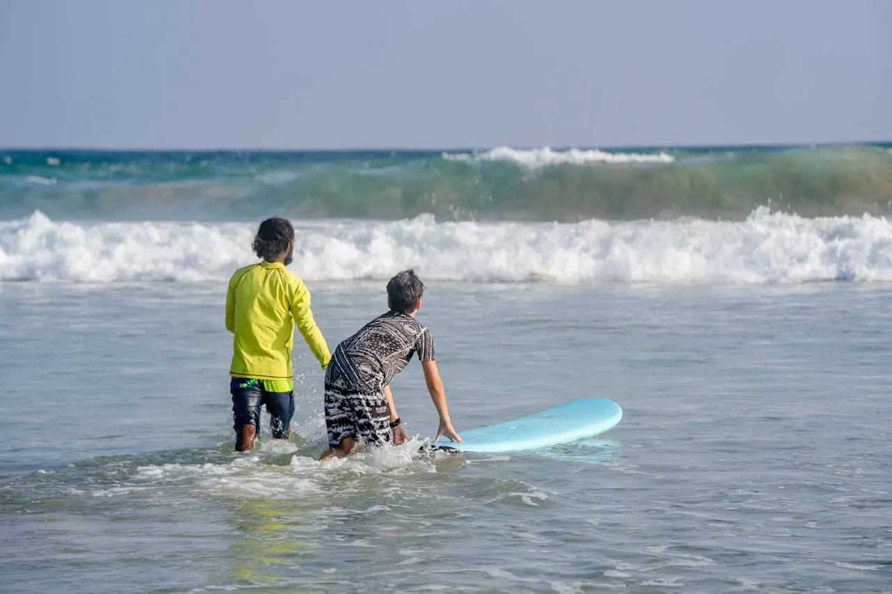 Beginner surfer riding a wave at Manuel Antonio Beach with a palm-lined Costa Rican coast in the background