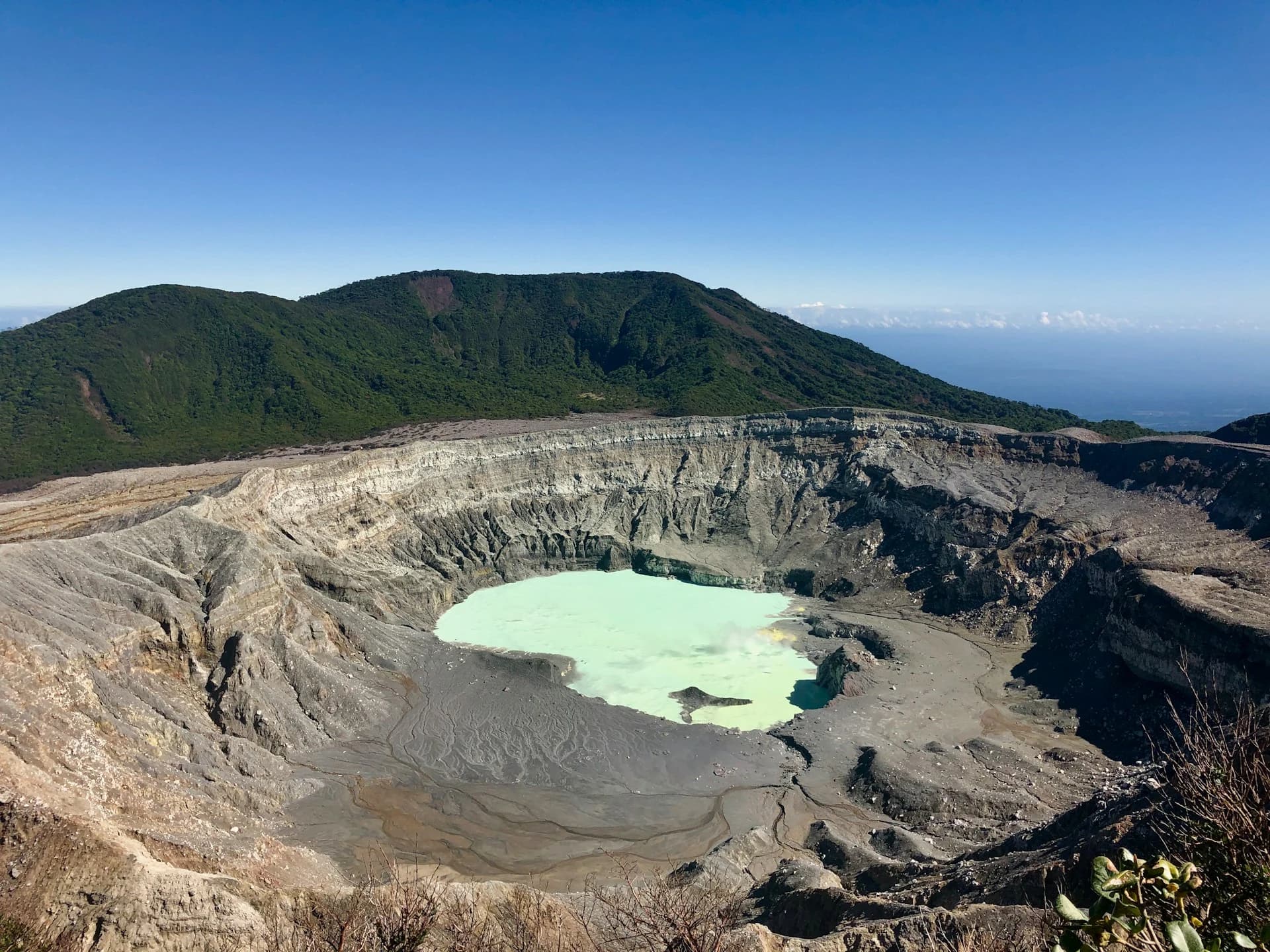 Visitors at the Poás Volcano crater viewpoint looking down at the steaming acid lake through drifting cloud