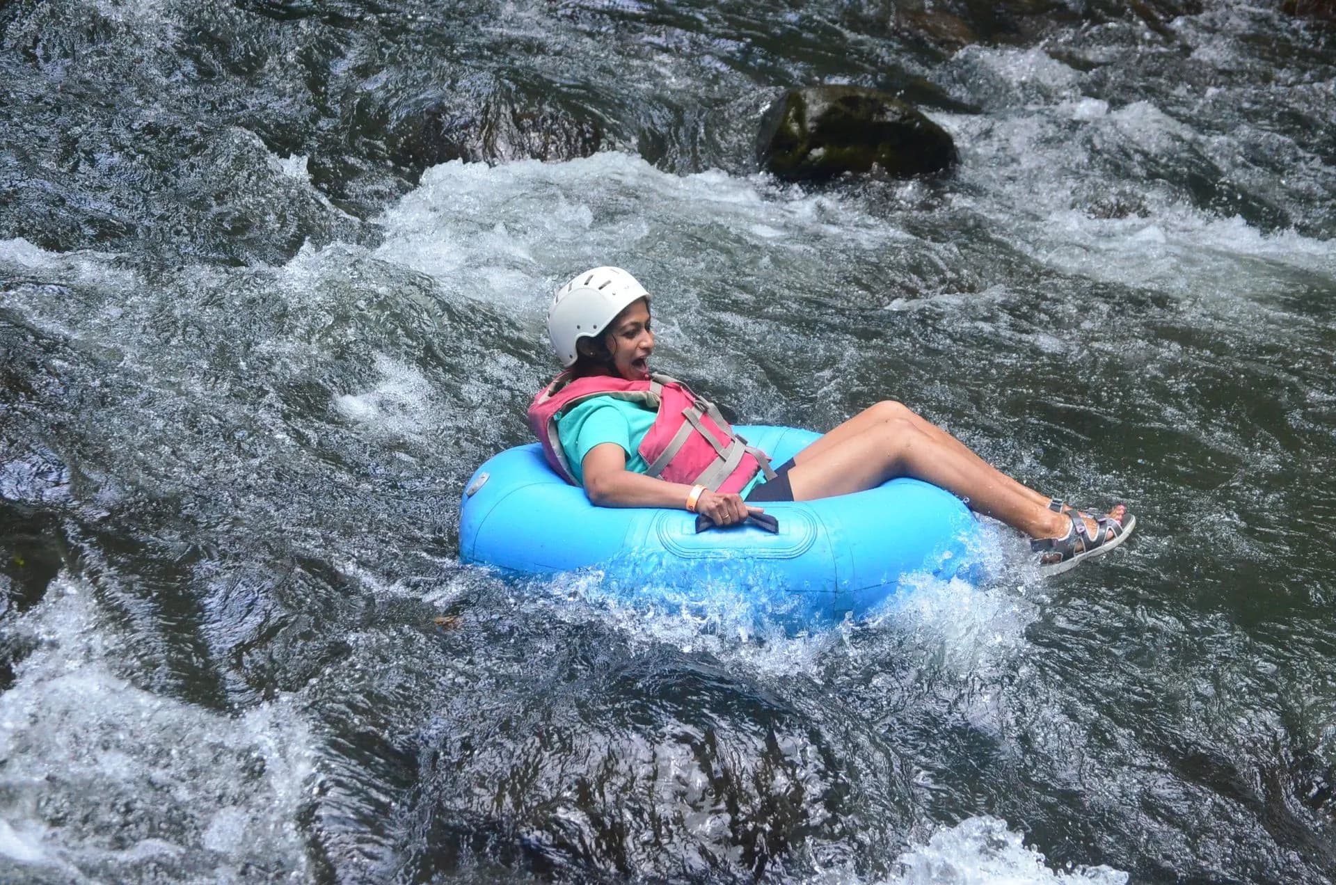 Tubers floating down the turquoise blue water of the Rio Celeste through rainforest near Tenorio Volcano, Costa Rica