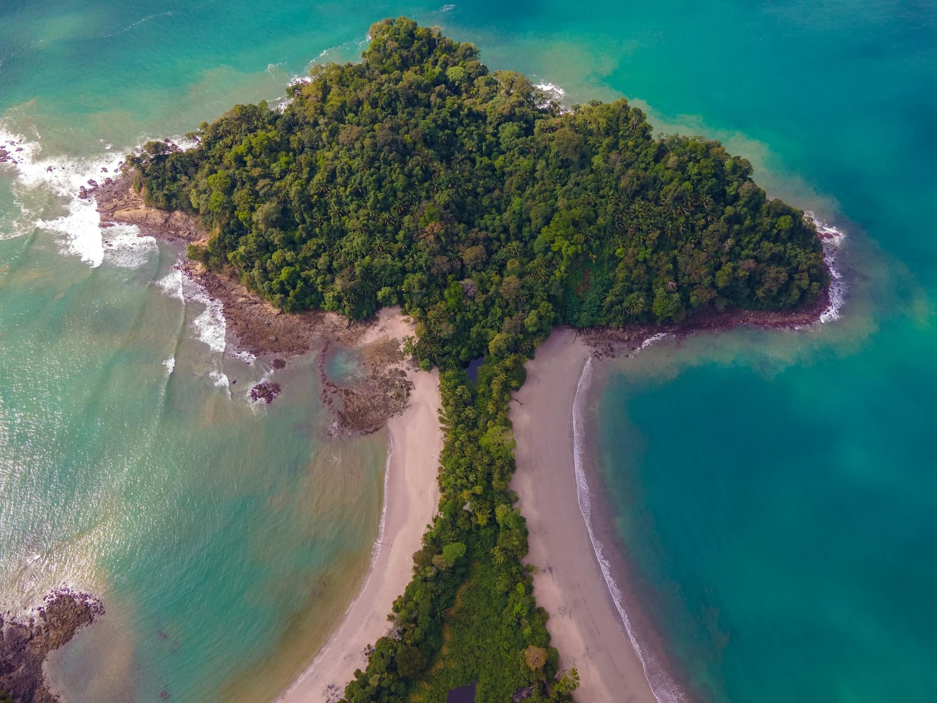 Forested cliffs meeting white sand and turquoise water at Manuel Antonio National Park, Costa Rica