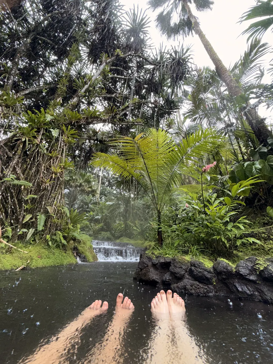 Guest lounging in a secluded natural thermal pool during a rainstorm at Tabacón Hot Springs Resort, La Fortuna